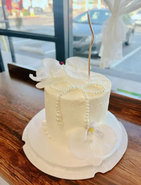 #412 elegant white birthday cake with sculpted bow, pearl chains and gold accents by KK Bakery in Rosemead
