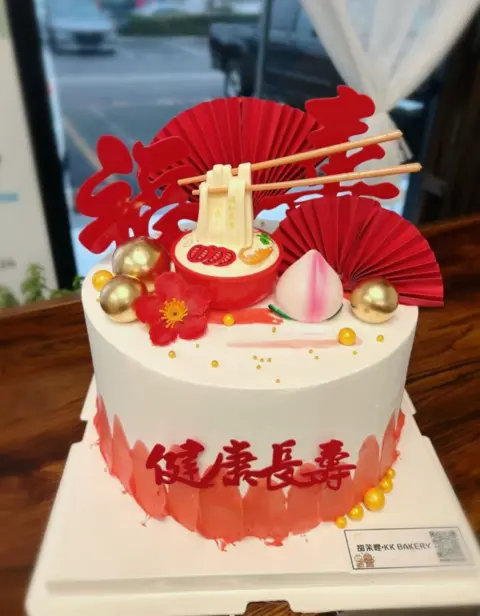 #420 Chinese longevity cake with peach decorations, red fan and gold pearl accents by KK Bakery in Rosemead