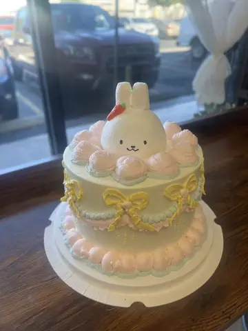 #626 pastel Miffy inspired birthday cake with bunny topper, pink cream puffs and yellow bows by KK Bakery in Rosemead