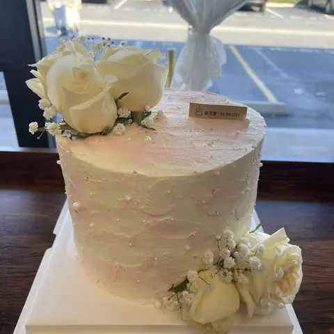 #644 tall white floral cake with fresh white roses, baby's breath and pearl details by KK Bakery in Rosemead